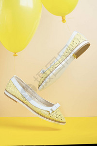 一对黄色夏季皮革女鞋在黄色的气球上飞图片