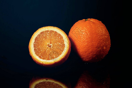 黑色背景上滴着水和溅水的橙子图片