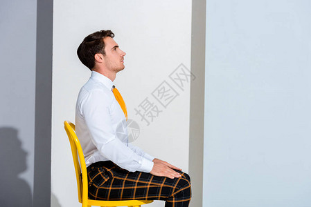 坐在白色和灰色的格子裤的男人的侧面视图图片