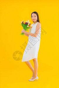 黄色孤立背景花朵的美丽年轻的年轻亚洲妇女图片