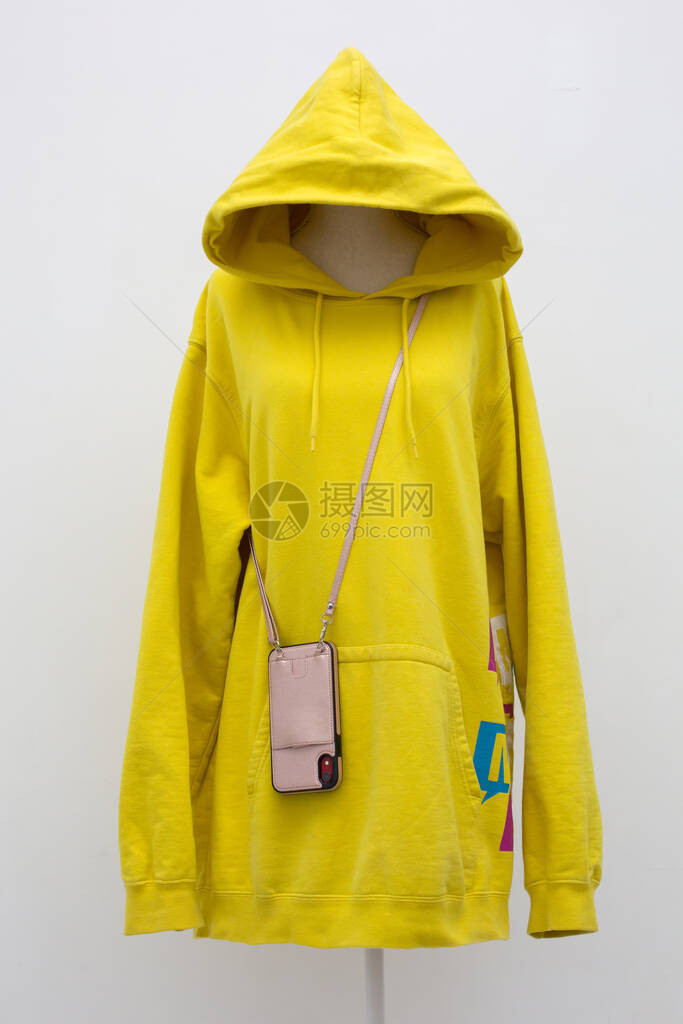 现代青少年穿着黄色长连帽衫智能手机装在带肩的斜挎包中的图片