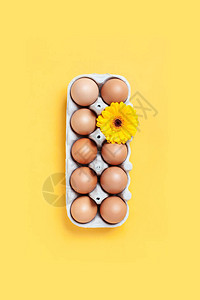 一盒棕色的鸡蛋和一朵黄色的花图片
