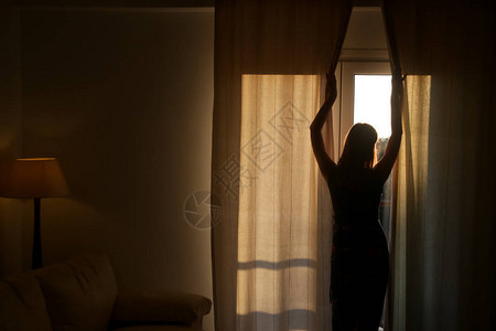 女人在一个房间开窗帘图片
