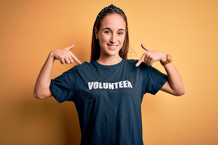 身穿义工T恤的年轻美女在黄色背景下从事志愿工作图片