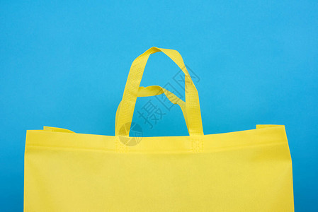 蓝色背景上可重复使用的黄色粘胶袋塑料图片