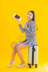 黄色孤立背景中带旅行李护照和登机牌的美丽亚洲图片