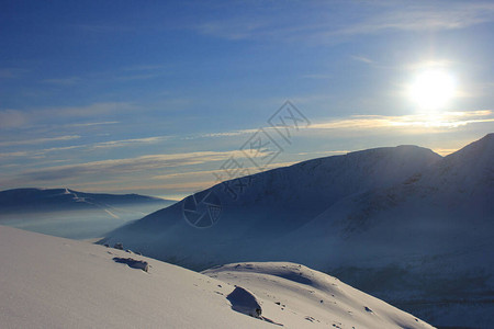 在雪峰的明亮的冬天太阳图片