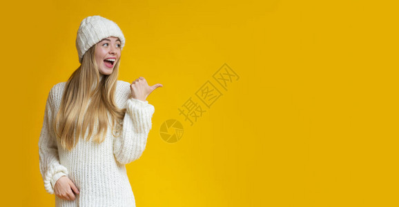 穿着白编织衣服的漂亮女孩用拇指着黄色背景图片