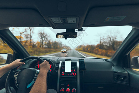 在汽车仪表盘的秋季高速公路旅行中用电话带白色屏图片