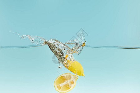 切柠檬在深水中滴落在蓝图片