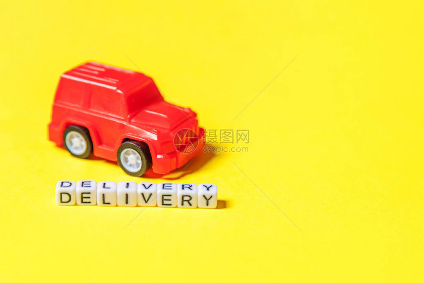 只需设计红色玩具车和在黄色彩背景上隔离的题词DELIVERY字网上购物网上购买电子商务包裹送货服务概图片
