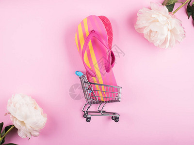玩具购物车中的女翻转手推车粉红色背景图片