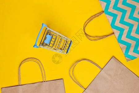 黄色背景上带有购物车和纸袋的样机快乐的客户概念网上购物网上商城消费主图片