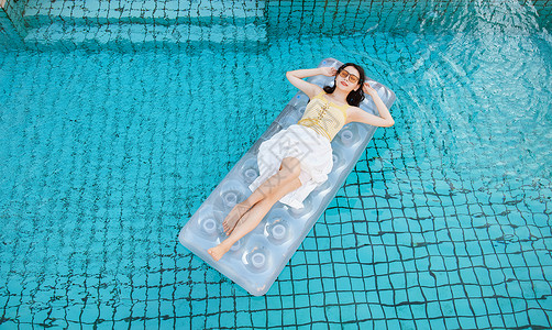 躺在泳池上放松的美女泳装高清图片素材