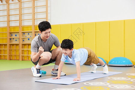 儿童体能素质教练给练习俯卧撑的男孩加油背景