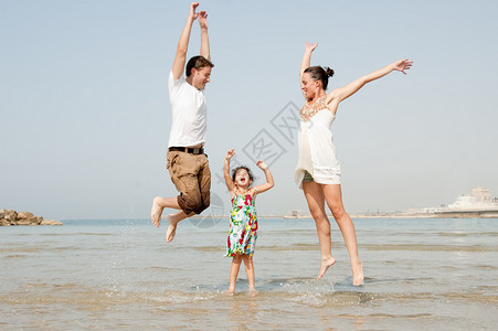 在沙滩上玩耍跳跃的父女俩背景图片