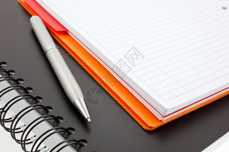 银笔和两个纸质笔记本橙色和黑色图片