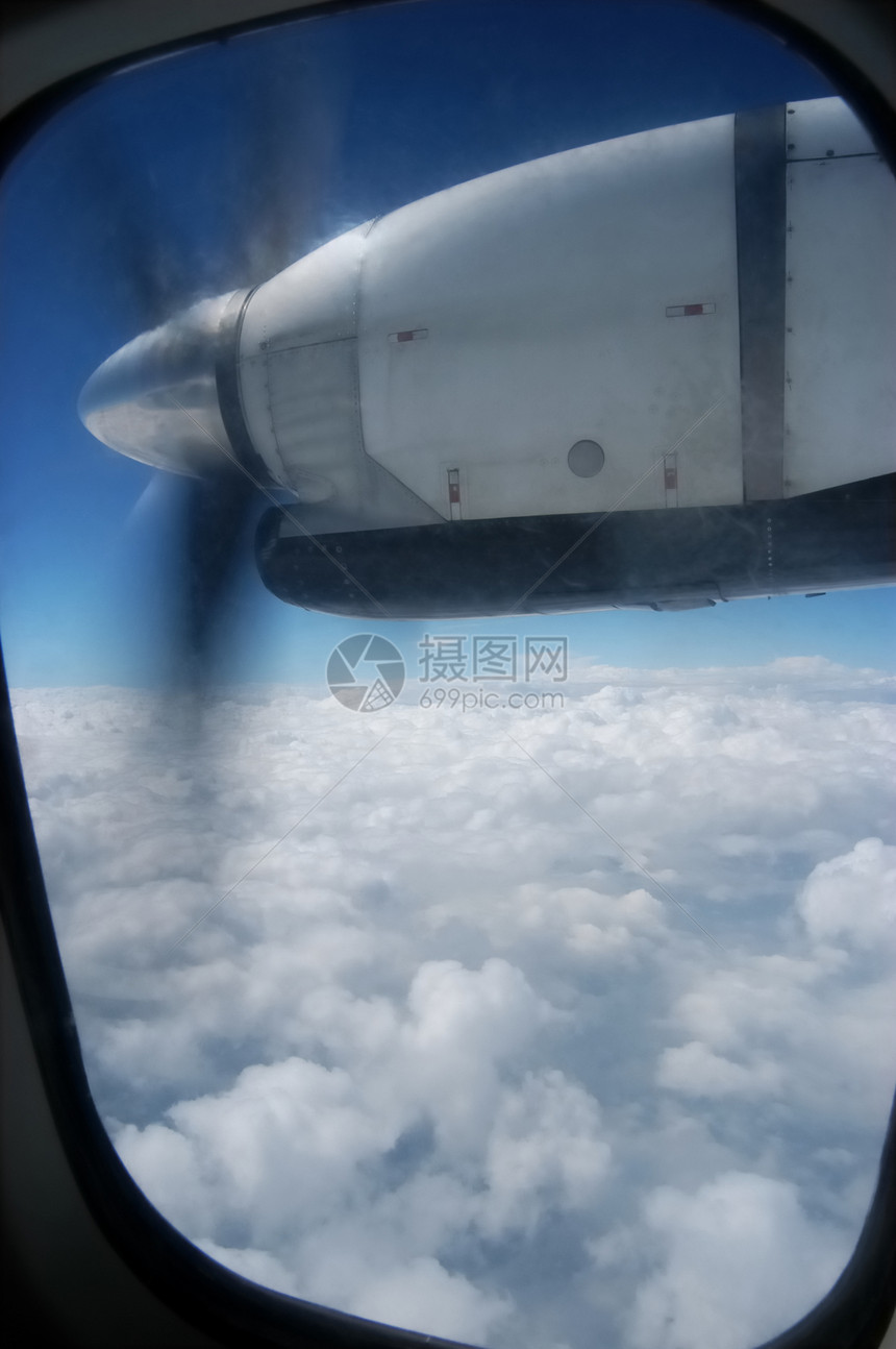 近距离关闭飞机上推进发动机舱观望Thru窗口美丽的白云和蓝图片