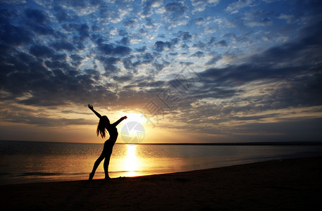 日落时女士在沙滩上做运动鲜活的颜色图片