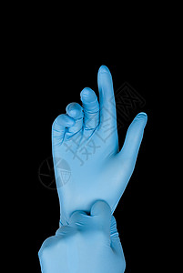 黑色背景的手上的蓝手套B图片