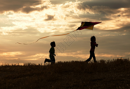 两个孩子喜欢在日落时放风筝图片