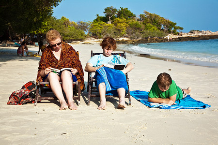 家庭享受阳光放松坐在沙滩图片
