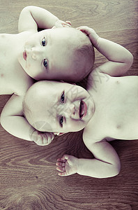 两个在木地板上哭泣的双胞胎宝贝背景图片