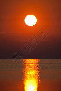在平静的海面上的红色日落图片