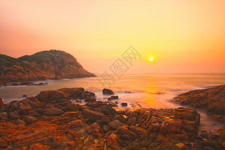日出时沿海岸的海石背景图片