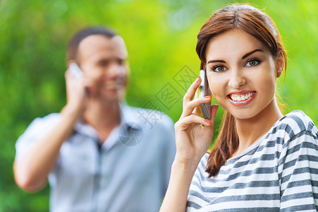 年轻美丽的一对快乐的情侣女人讲电话背景在夏图片