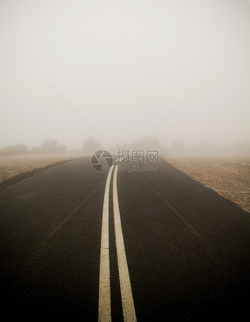 带有双线的黑暗道路消失在非常浓密的雾中图片