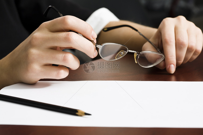 桌子上的纸和铅笔拿着眼镜的人手图片