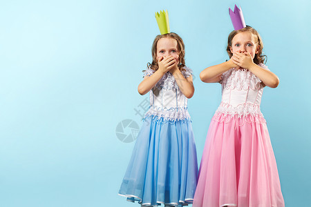 双胞胎女孩的肖像穿着漂亮的裙子和皇冠展图片