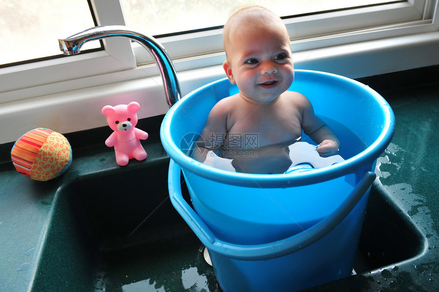 在一个蓝色水桶里的婴儿在夏天的炎图片