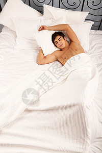 在枕头下用一只手在睡舒适的床上睡觉的图片