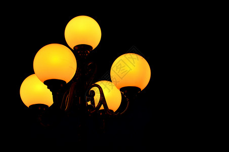 路灯在漆黑的夜色中闪烁着温暖的球体图片