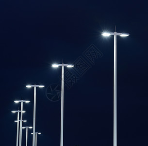 现代街道灯在夜晚对着黑高清图片
