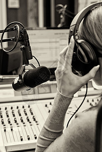 在收音机麦克风前工作的女DJ的后图片