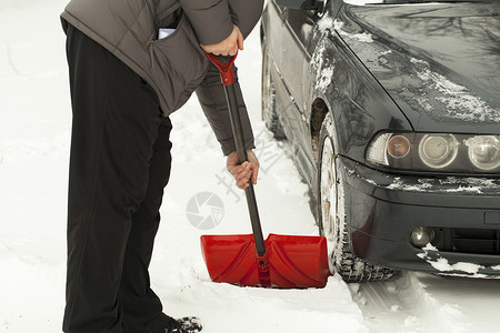 有铲子的人清除汽车周围的雪图片