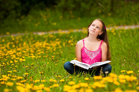 小女孩坐在草地上看书做梦图片