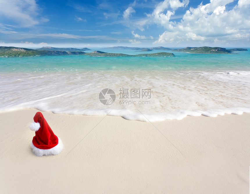 白色沙滩热带海滩上的圣诞老人帽子图片