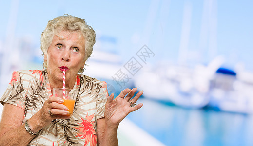 在户外用稻草喝果汁的女人图片