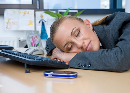 睡在办公桌前的疲惫女商人图片