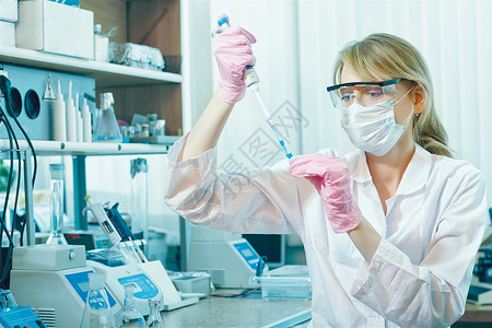 实验室中身戴防护手套眼镜和面具的年轻女科学家肖像图片