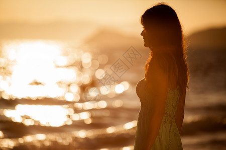 傍晚日落时分在海滩上的年轻女子高清图片