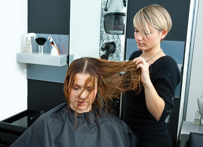 发型师在沙龙用吹风机吹干女人头发图片