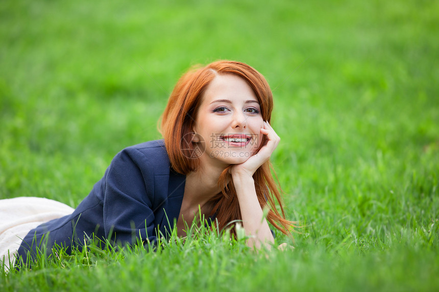 躺在绿草丛中的红发女人图片
