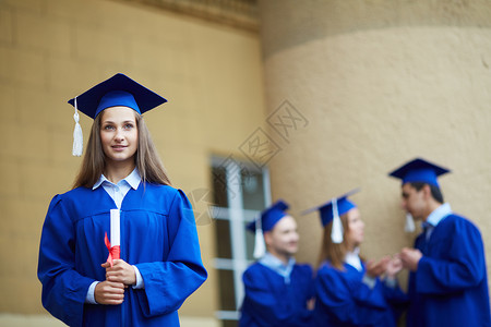 友好学生在毕业礼服中与前面的图片
