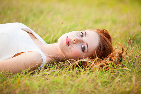 躺在草地上的红发女孩背景图片