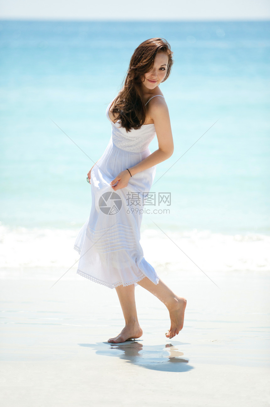 迷人的亚洲女在海滩上散步看着图片